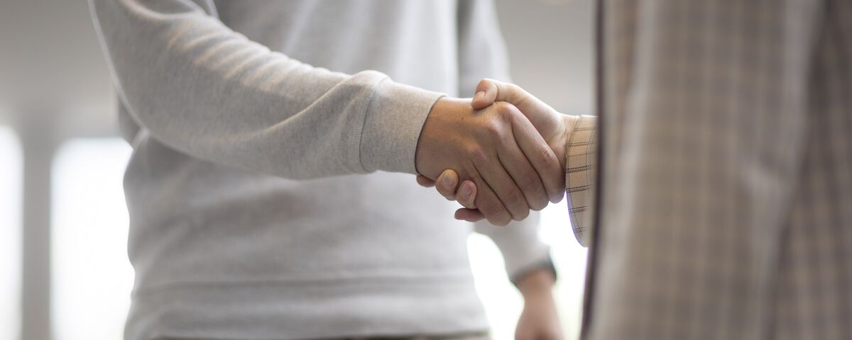 Man and woman shaking hands in office building.