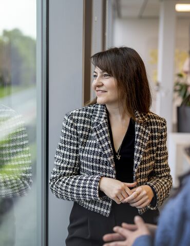 Woman looking out of window of office building.