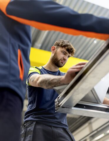 Warehouse employees assembling aluminium frame.